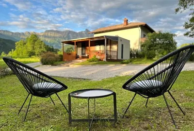 two chairs sitting in the grass in front of a house at Hiša Uran in Kobarid