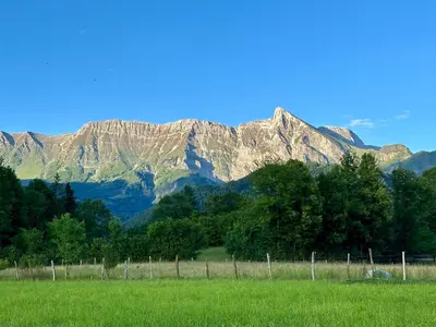 a fence in a field with mountains in the background at Hiša Uran in Kobarid