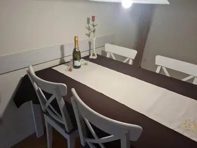 a dining room table with a bottle of wine and chairs at Apartma Svit in Kranjska Gora