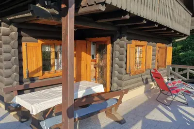 a porch of a house with a table and a chair at Cottage in the woods - Lake Bohinj in Bohinj