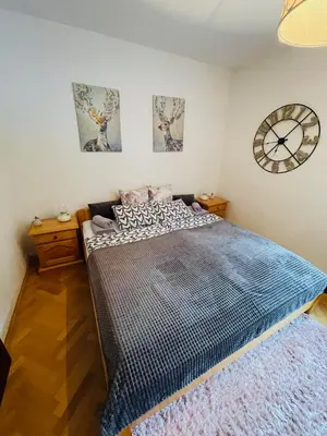 a bedroom with a large bed and a clock on the wall at APARTMA ODKLOP Rogla in Lukanja