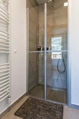 a shower with a glass door in a bathroom at Maple & Pine Bled in Bled