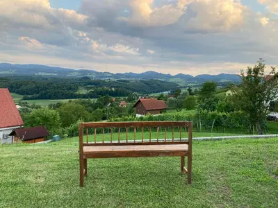a wooden bench sitting on top of a field at Morning coffee w a view :) in Podčetrtek
