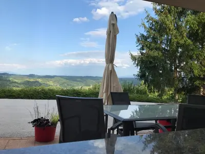 a table with a closed umbrella and a table and chairs at Morning coffee w a view :) in Podčetrtek