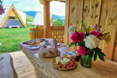 a table with a vase of flowers and food on it at Glamping Brodej in Vitanje