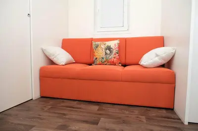 an orange couch with two pillows on it in a room at VINEA PANONIKA wine & mind retreat in Radenci