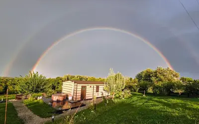 a rainbow in the sky over a house at VINEA PANONIKA wine & mind retreat in Radenci