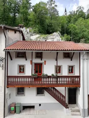 a white house with a balcony and a staircase at Hiša pod Gradičem in Kobarid