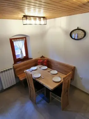 a dining room table with chairs and a clock on the wall at Hiša pod Gradičem in Kobarid