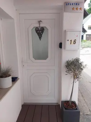 a white door with a sign on it next to a plant at Apartment Dajana in Bovec
