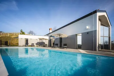 a swimming pool in front of a house at Larya House in Dobrovo