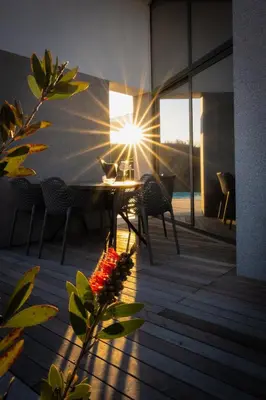 a table and chairs on a balcony with the sun shining at Larya House in Dobrovo