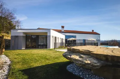 a large white house with a stone wall at Larya House in Dobrovo