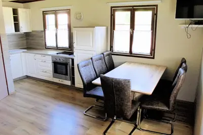 a kitchen with a wooden table and chairs in it at Hiška Čatež in Brežice