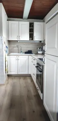 a white kitchen with wooden floors and white cabinets at Hiška Čatež in Brežice