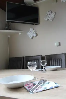 a wooden table with two plates and glasses on it at Hiška Čatež in Brežice