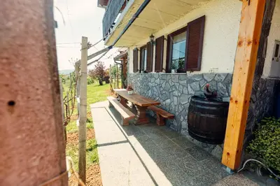 a wooden bench next to a building with a barrel at Zidanica Bahor in Črnomelj