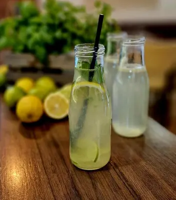 two bottles of lemonade sitting on a wooden table at Gostilna s prenočišči Pri Janezu in Zgornja Ložnica