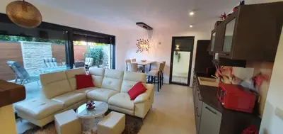 a living room with a white couch and a kitchen at Apartma Archy in Moravske Toplice