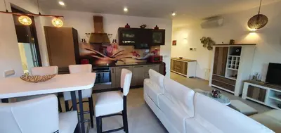 a kitchen and living room with white chairs and a table at Apartma Archy in Moravske Toplice