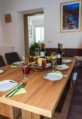 a wooden table with wine bottles and glasses on it at Hiša Bohinc z wellnessom in Tolmin