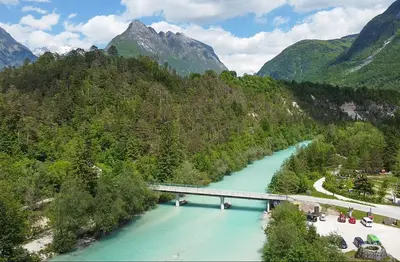 a bridge over a river with mountains in the background at Holiday apartment Pika in Bovec