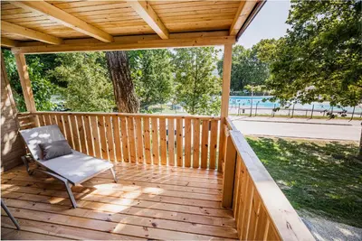 a wooden deck with a chair sitting on it at Premium Mobile Tree House with Thermal Riviera Tickets in Čatež ob Savi