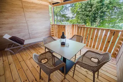 a patio with a table and chairs on a deck at Premium Mobile Tree House with Thermal Riviera Tickets in Čatež ob Savi