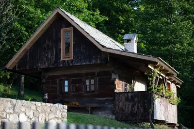 a log cabin with a stone fence in front of it at HIS-a za 2 in Dragatuš