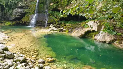 a waterfall in a river with green water at Hiša Lojz in Žaga