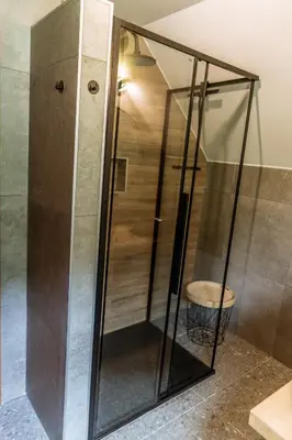 a glass shower with a stool in a bathroom at Hiša Lojz in Žaga