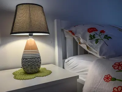 a lamp sitting on a table next to a bed at Sobe - rooms R&K in Bohinj