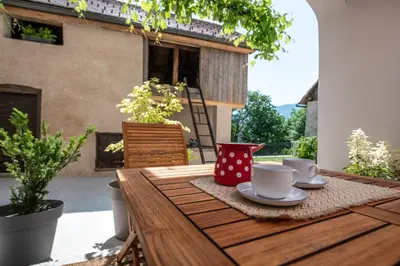 a wooden table with cups and saucers on a patio at MEŽNARIJA Radovljica in Radovljica