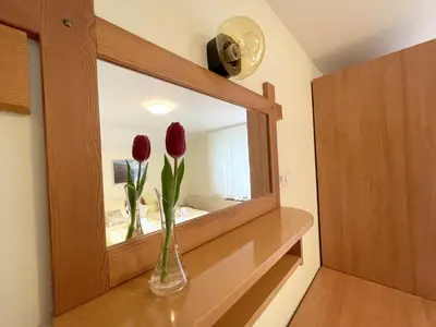 a mirror with two flowers in a vase on a shelf at Apartmaji Preželj in Bohinj