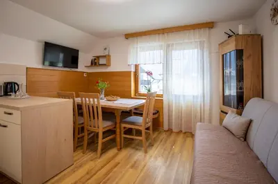 a kitchen and dining room with a table and a couch at Apartmaji Preželj in Bohinj