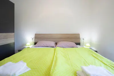 a bedroom with a yellow bed with two pink pillows at Apartment Bistra Kranjska Gora in Kranjska Gora