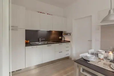 a kitchen with white cabinets and a sink and a table at Apartments Smreka Kranjska Gora in Kranjska Gora