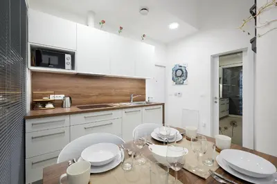 a kitchen with a wooden table and white cabinets at Apartments Smreka Kranjska Gora in Kranjska Gora