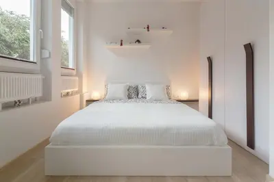 a white bedroom with a white bed and two windows at Apartments Smreka Kranjska Gora in Kranjska Gora