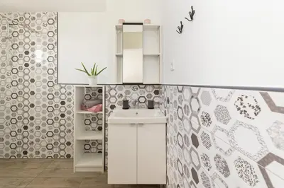 a white kitchen with a sink and a tile wall at Pod Koblo Bohinj Apartments in Bohinj