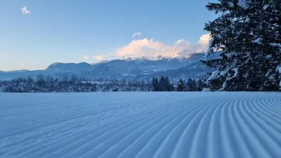 a snow covered field with mountains in the background at Pod Koblo Bohinj Apartments in Bohinj