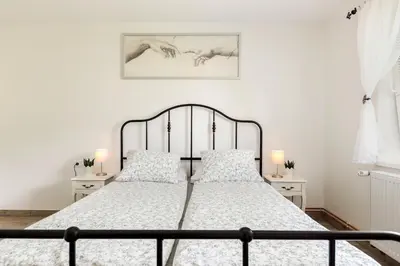 a white bedroom with a metal bed with pillows at Pod Koblo Bohinj Apartments in Bohinj