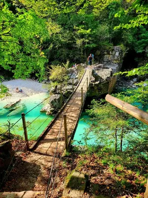 a person walking across a wooden bridge over a river at Apartma Kati in Bovec