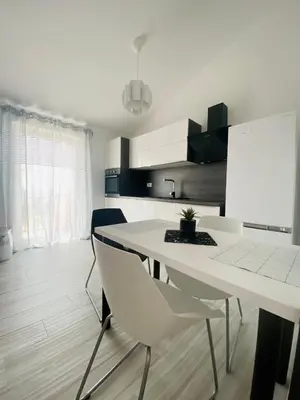 a white kitchen with a white table and chairs at Apartma Mija-Dekani in Dekani