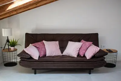 a brown couch with pink and white pillows on it at Apartmaji na placu in Renče