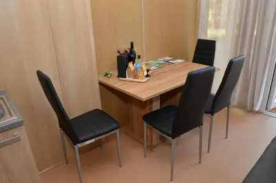 a dining room table with four chairs in a room at Počitniške hiške Murania in Trimlini