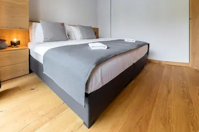 a large bed in a bedroom with a wooden floor at Hiša Križaj in Bohinj
