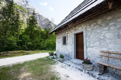 a stone building with a wooden door next to a mountain at Mountain heart holiday house in Trenta