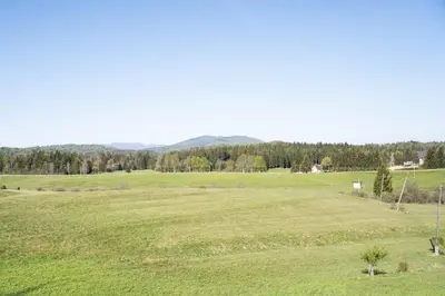a large green field with mountains in the background at Apartma Sveti Duh in Nova Vas