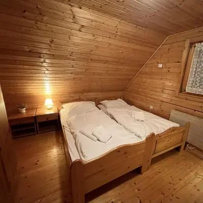 a bedroom with a bed in a wooden room at Hiška Marjetica in Podčetrtek